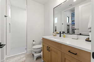 Bathroom with a tile shower, vanity, and toilet