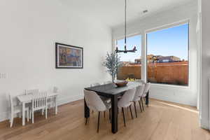 Dining space with light wood-type flooring and an inviting chandelier