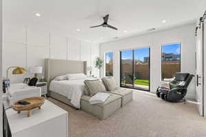 Carpeted bedroom with access to exterior, ceiling fan, and a barn door