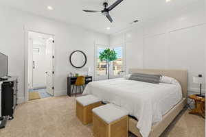 Bedroom with light colored carpet, ensuite bath, and ceiling fan