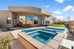 Rear view of property featuring a lawn, a pool with hot tub, and a patio area