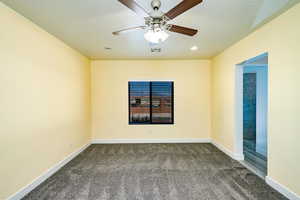 Carpeted spare room featuring ceiling fan