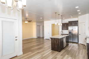 Kitchen featuring pendant lighting, sink, an island with sink, dark brown cabinets, and stainless steel appliances