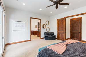 Carpeted bedroom featuring connected bathroom and ceiling fan