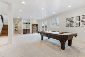 Game room with light carpet, bar area, and billiards