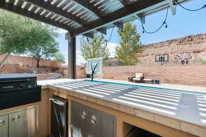 View of patio with a pergola and area for grilling