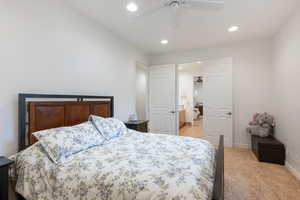 Bedroom with ceiling fan, ensuite bathroom, and light carpet