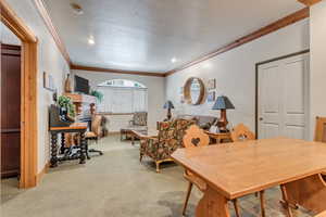 Dining room featuring a textured ceiling, light colored carpet, and crown molding