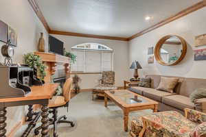 Carpeted office featuring a tiled fireplace, a textured ceiling, and ornamental molding