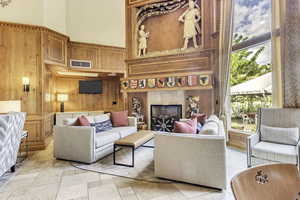 Living room featuring wood walls, a high ceiling, and a tiled fireplace