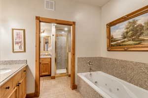 Bathroom with tile patterned floors, separate shower and tub, and vanity