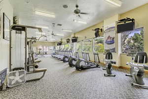Exercise room with ceiling fan and a textured ceiling