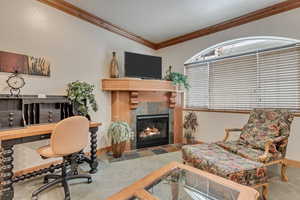 Carpeted home office with crown molding, a fireplace, and vaulted ceiling