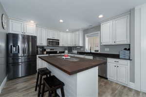 Kitchen featuring wood counters, a center island, stainless steel appliances, and white cabinets