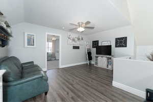 Living room with ceiling fan, dark hardwood / wood-style flooring, and lofted ceiling