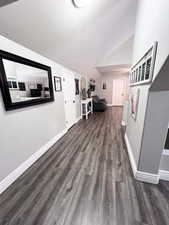 Hall with dark wood-type flooring and vaulted ceiling