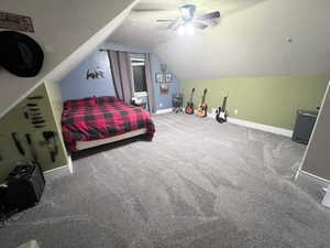 Carpeted bedroom with ceiling fan and lofted ceiling