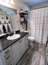 Full bathroom with hardwood / wood-style flooring, vanity, toilet, and shower / bathtub combination with curtain