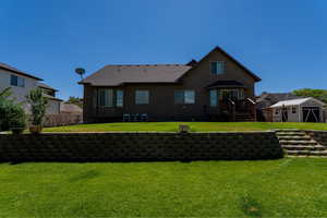 Back of house with a storage shed and a lawn