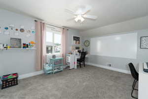 Carpeted office space featuring vaulted ceiling and ceiling fan