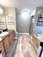 Full bathroom featuring hardwood / wood-style flooring, vanity, separate shower and tub, and toilet