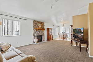 Living room with a fireplace, carpet floors, vaulted ceiling, and ceiling fan