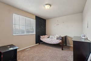 Bedroom with light colored carpet and a textured ceiling