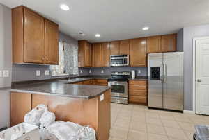 Kitchen featuring kitchen peninsula, light tile patterned floors, stainless steel appliances, and sink