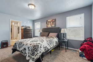 Carpeted bedroom with ensuite bathroom and a textured ceiling