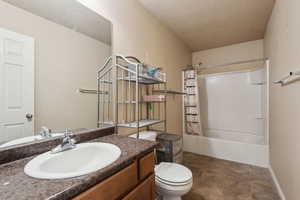 Full bathroom with vanity, toilet, a textured ceiling, and shower / tub combo