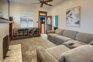 Living room featuring carpet flooring, ceiling fan, and a brick fireplace