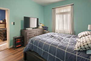 Bedroom with a wood stove and hardwood / wood-style flooring