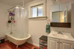 Bathroom featuring hardwood / wood-style floors, shower / bath combination with curtain, and vanity