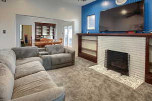 Living room featuring a fireplace, carpet, and ceiling fan