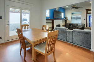 Dining area with ceiling fan, a fireplace, and light hardwood / wood-style flooring