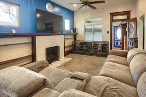 Living room featuring a fireplace, carpet floors, and ceiling fan