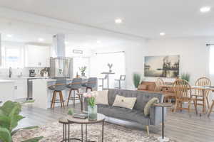 Living room featuring beamed ceiling, sink, and light hardwood / wood-style flooring