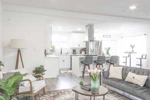 Living room featuring beamed ceiling, wood-type flooring, and sink