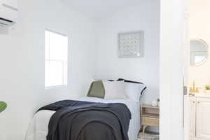 Bedroom featuring a wall mounted AC and lofted ceiling