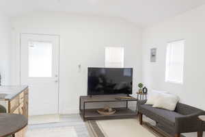 Living room with light wood-type flooring, vaulted ceiling, and a wealth of natural light