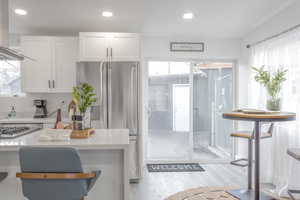 Kitchen featuring stainless steel appliances, white cabinetry, plenty of natural light, and light hardwood / wood-style flooring