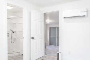 Bathroom featuring hardwood / wood-style flooring, a wall unit AC, and walk in shower