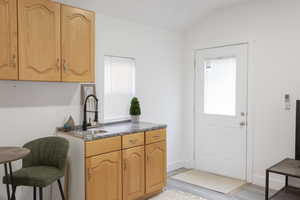 Kitchen with vaulted ceiling, sink, plenty of natural light, and light hardwood / wood-style flooring