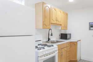 Kitchen with light wood-type flooring, white appliances, and sink