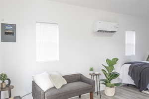 Living area with an AC wall unit and hardwood / wood-style floors