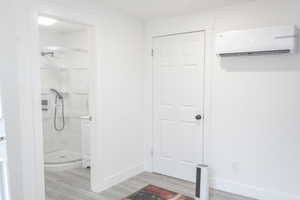 Bathroom featuring a wall mounted AC, a shower, and hardwood / wood-style flooring