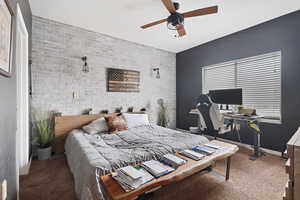 Bedroom featuring carpet flooring, ceiling fan, and brick wall