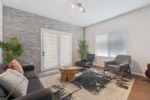 Interior space featuring carpet floors, rail lighting, and brick wall