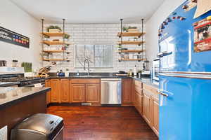 Kitchen featuring dark hardwood / wood-style flooring, stainless steel appliances, tasteful backsplash, and sink