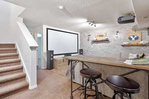 Home theater with light colored carpet and a textured ceiling